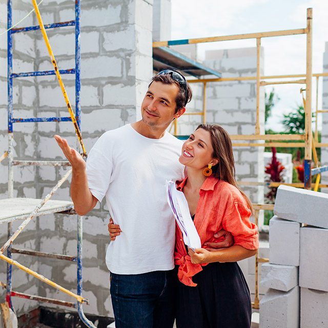 Happy young couple checking their future house under construction